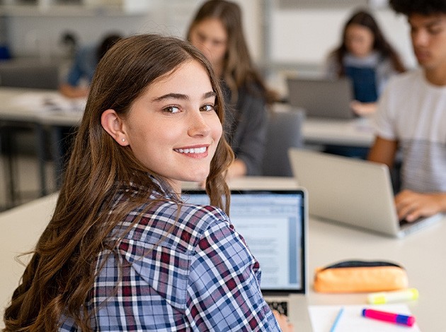 Teen girl smiling while working in classroom