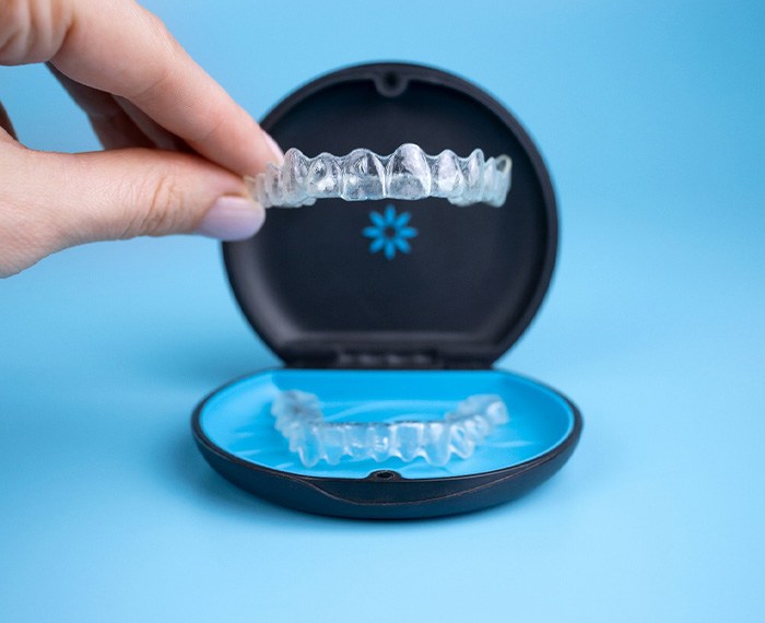 Fingers lifting Invisalign out of carrying case