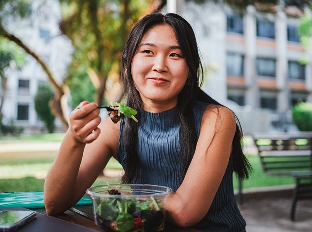 Teen girl smiling while eating lunch outside