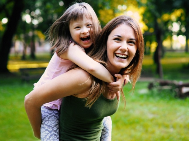 Mother giving piggyback ride to her daughter with special needs