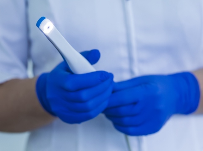 Dental team member holding thin white intraoral camera