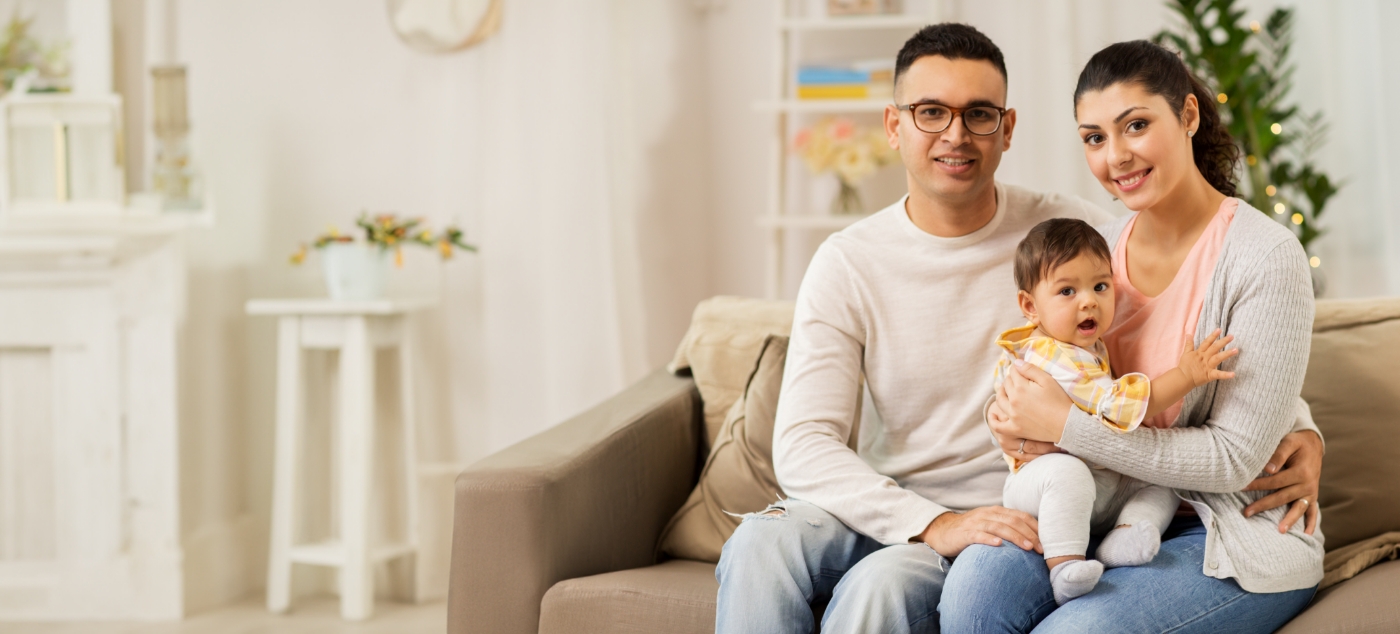 Man and woman sitting on couch with their baby