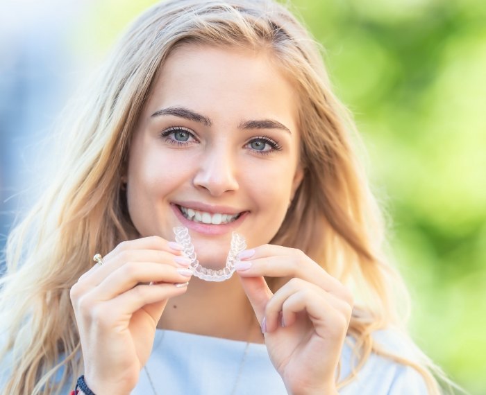 Smiling girl holding two retainers