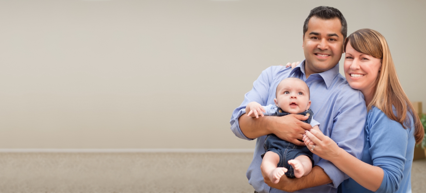 Man and woman smiling while holding their baby