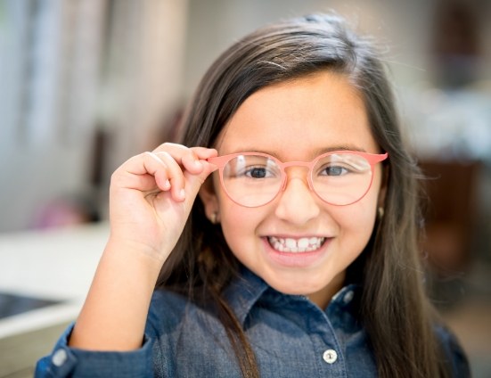 Young girl smiling and adjusting her glasses