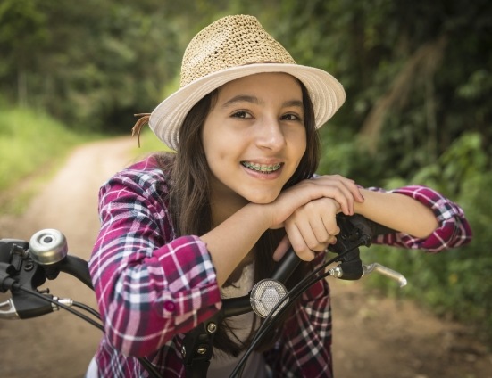 Teenage girl with braces smiling and sitting on her bike