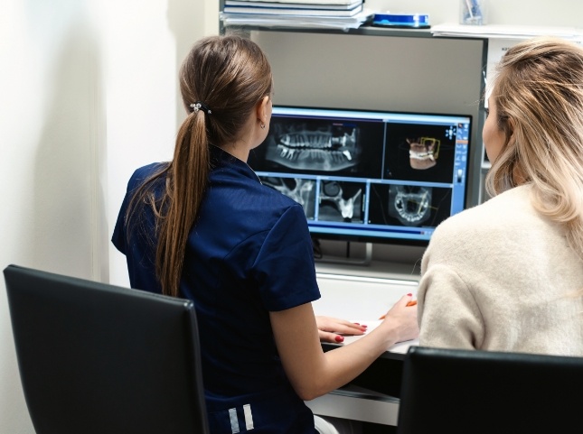 Dental team member showing a woman x rays of teeth on computer