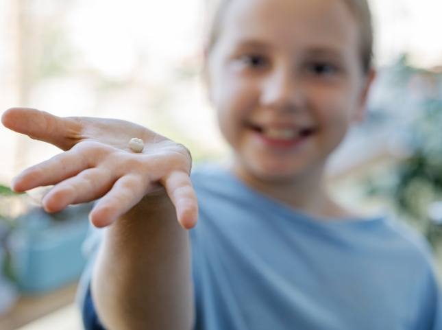 Smiling boy holding a tooth