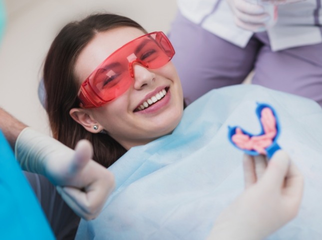 Teenage girl in dental chair with dental team member holding fluoride