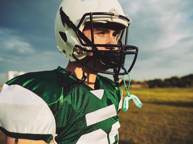 Football player with an athletic mouthguard hanging from his helmet