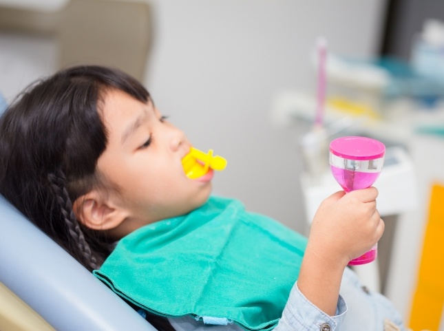 Young girl in dental chair with fluoride trays on her teeth