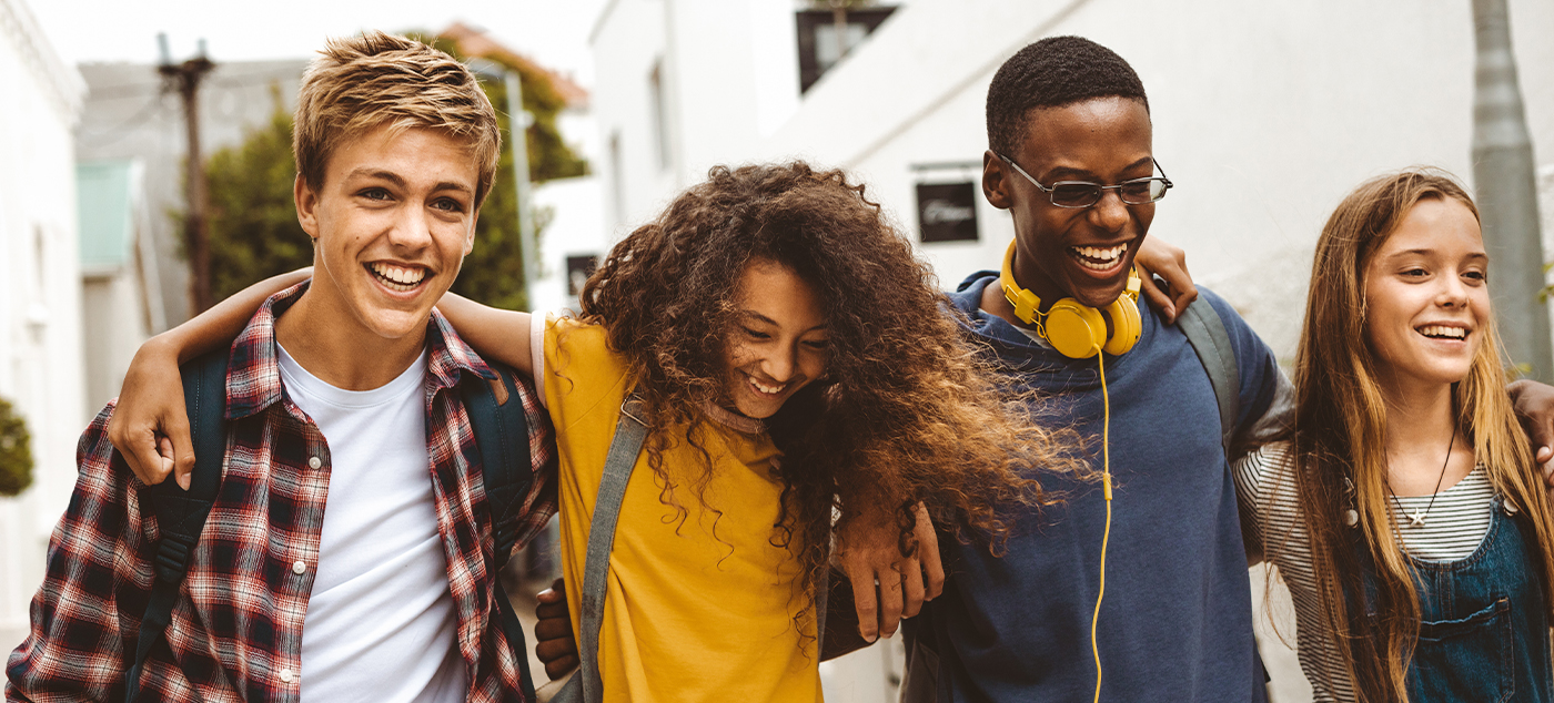 Four teens smiling together after visiting dentist for teens in Newark