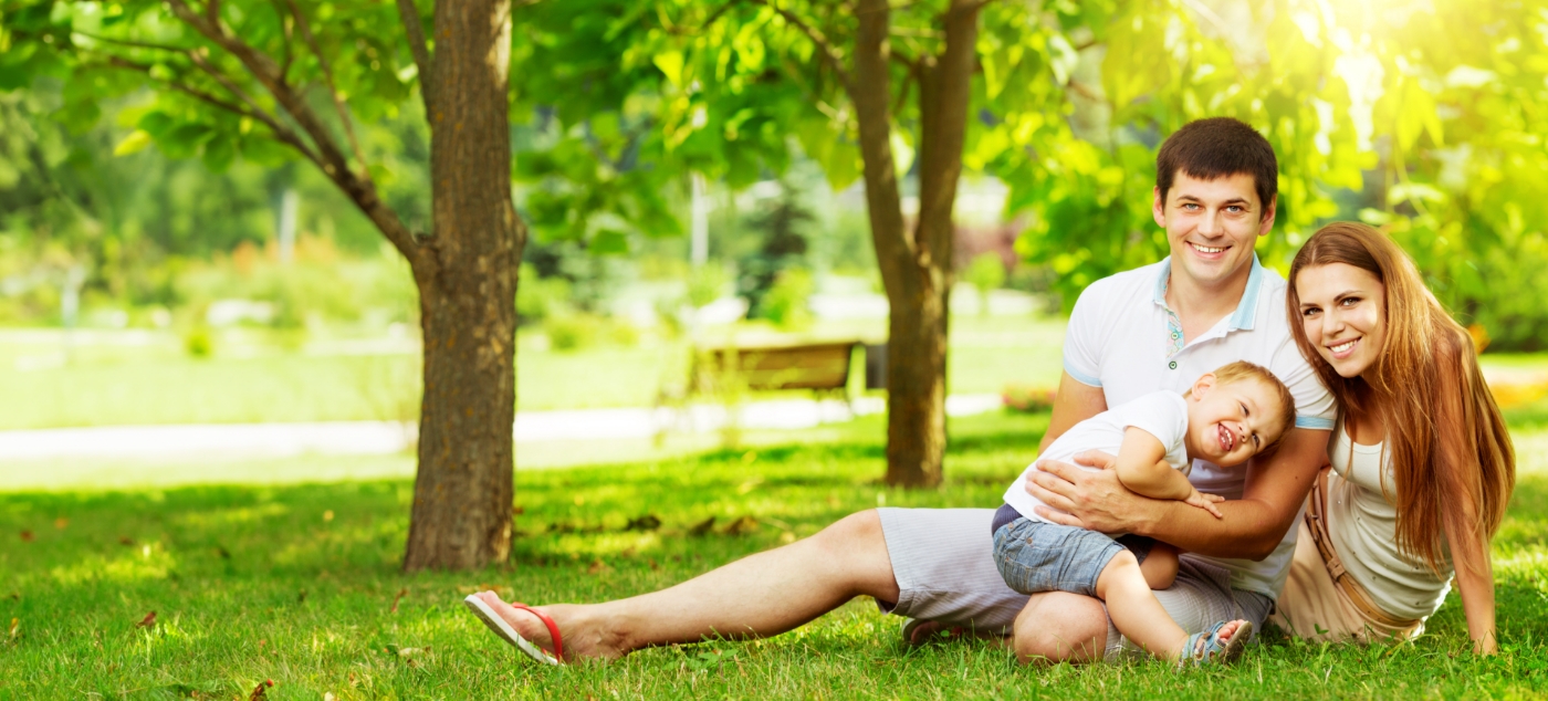 Family of three smiling in park after visiting dentist for toddlers in Newark