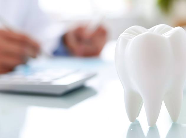 Large model tooth in foreground with person calculating invoice in background