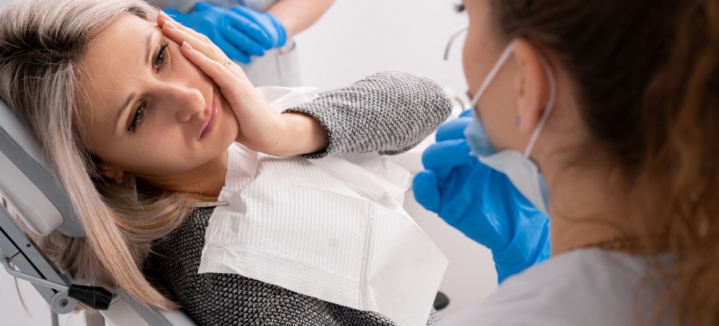 Girl holding her cheek in pain while talking to pediatric emergency dentist in Newark