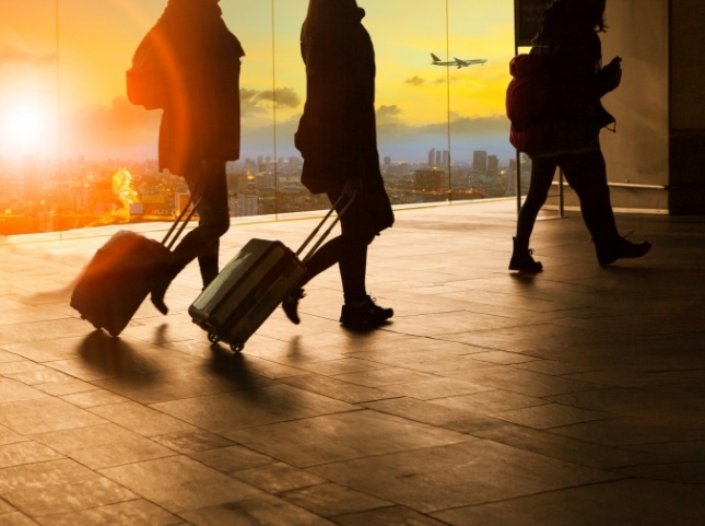 Three people wheeling suitcases in airport