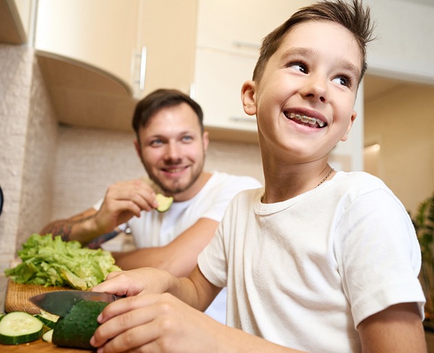 a boy with braces cutting a cucumber