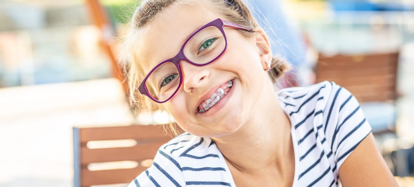 a smiling girl with braces and glasses