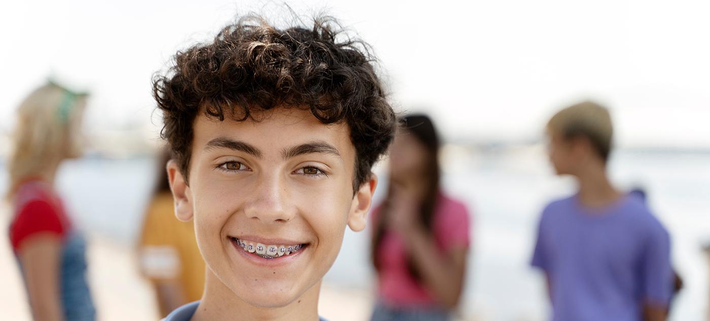 Teenage boy smiling and wearing traditional braces in Newark