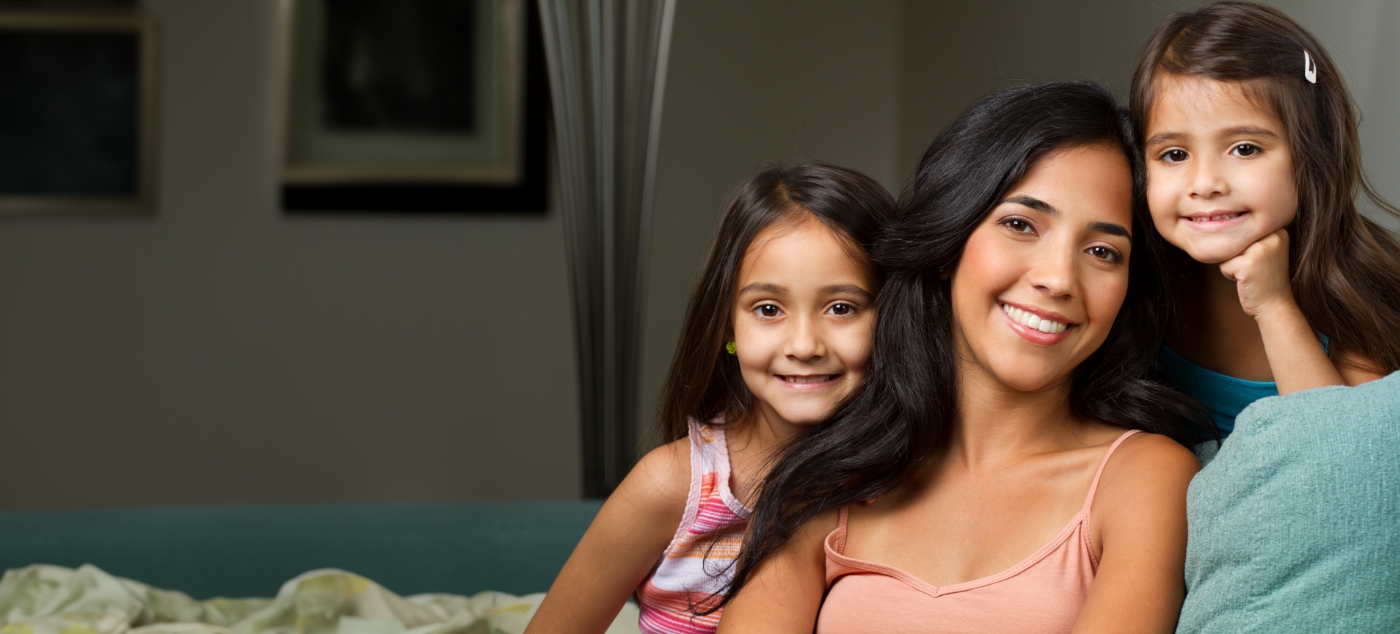 Mother smiling on couch with her two daughters