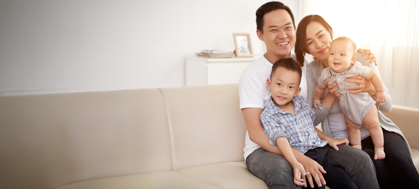 Family of four smiling smiling on couch after visiting pediatric special needs dentist