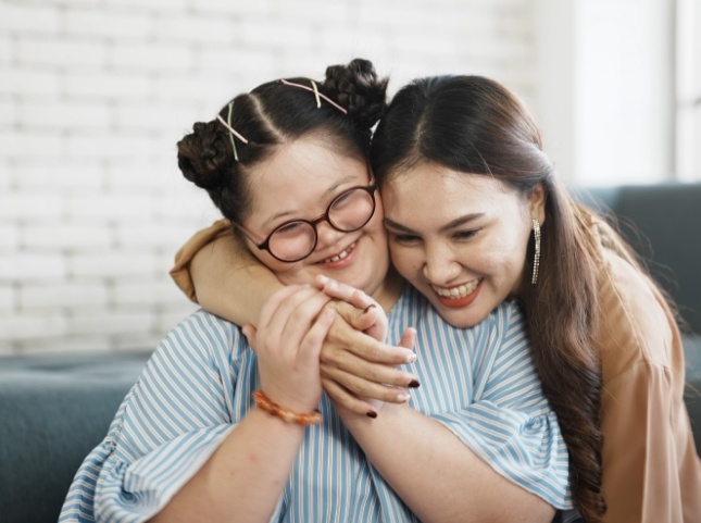 Young woman hugging a girl with special needs