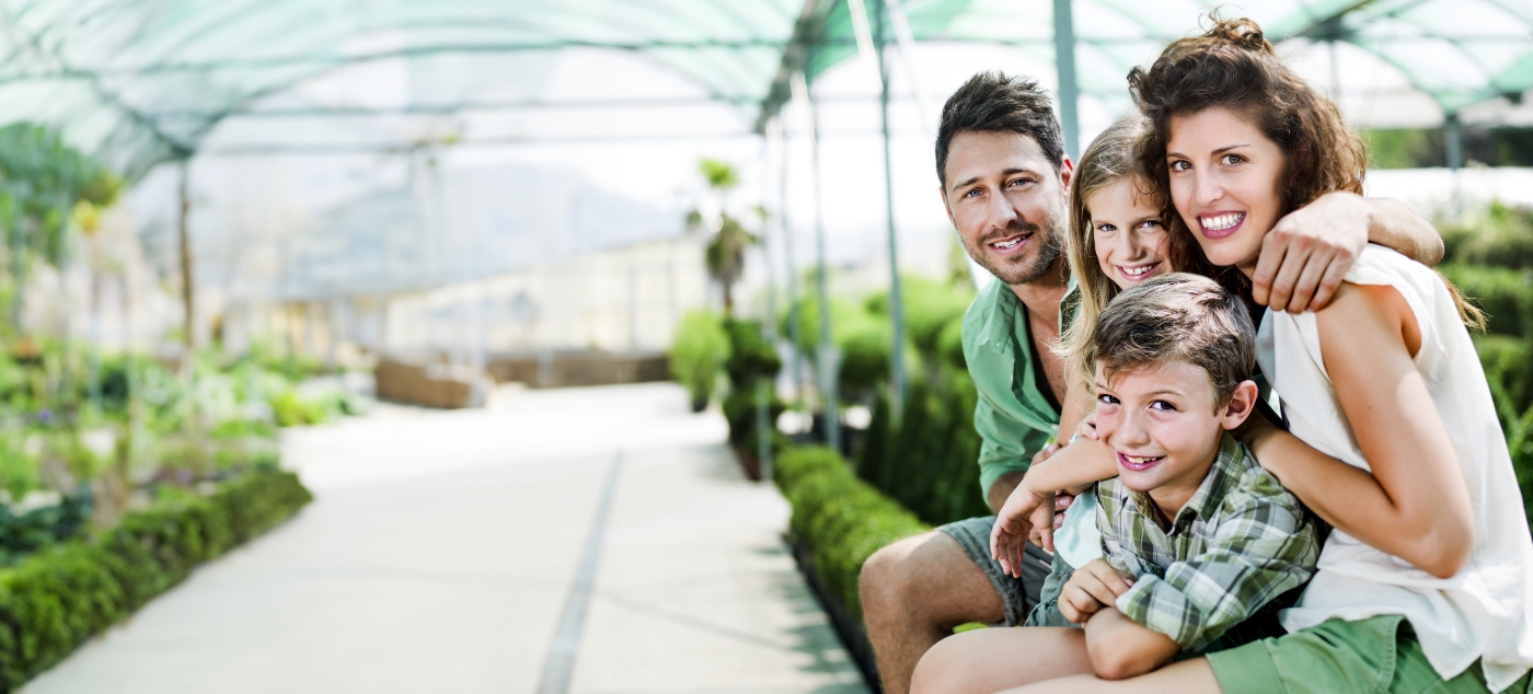 Family of four smiling on outdoor bench