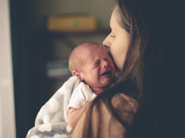 Baby weeps in mother’s arms